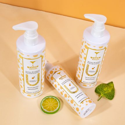 Three white pump bottles with yellow dotted labels standing on a pale yellow surface, plus a lime slice and a mint leaf beside them (hair care products).