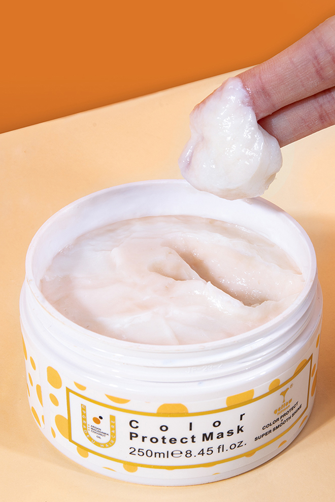 Close-up of a white cream in a jar labeled Color Protect Mask (250 ml); a finger lifts a dab of the paste above the container.