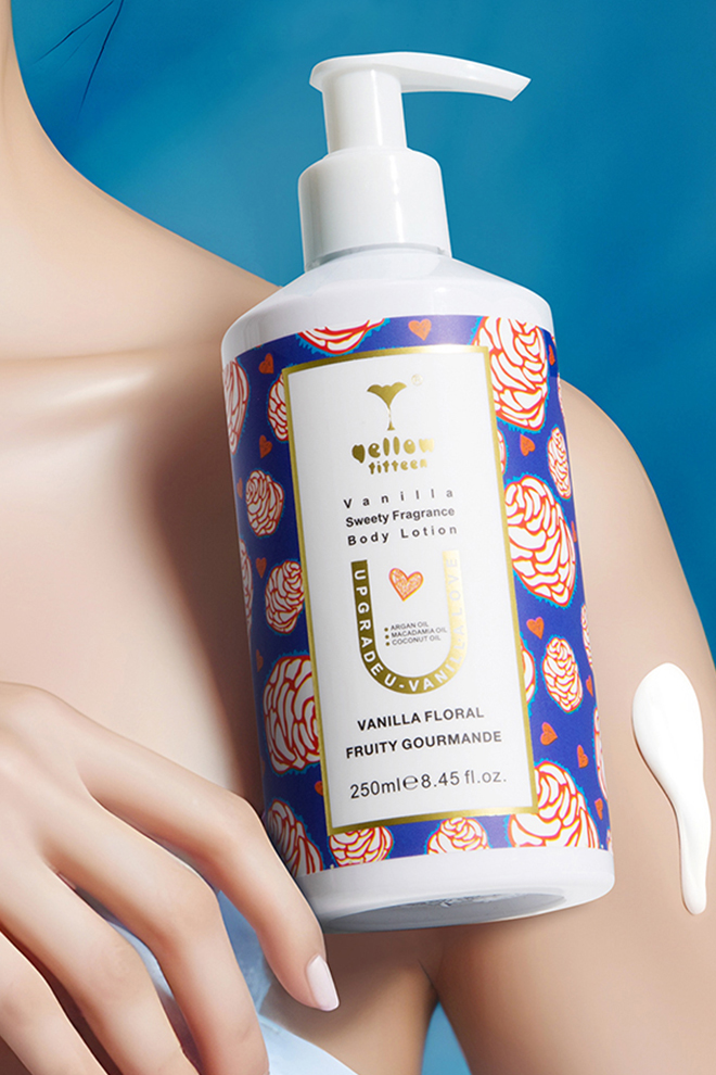 White pump bottle of Vanilla Floral body lotion with a blue floral-pattern label against a teal background, close-up.