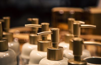 Close-up of metal pump dispensers on white lotion bottles in a row, with shallow depth of field blur in the background.