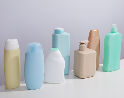 Assortment of pastel-colored plastic shampoo and lotion bottles lined up on a white surface.