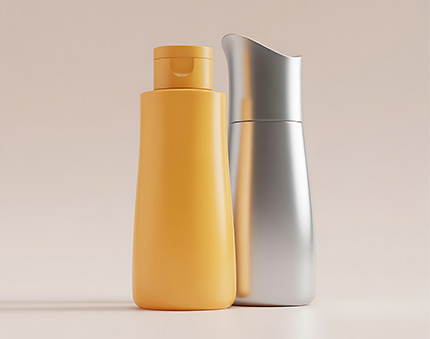 Two tall cosmetic bottles on a pale surface: a yellow plastic bottle in front of a silver pump bottle against a neutral backdrop.