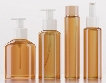 Set of four amber cosmetic bottles with white pump or dropper caps in a row, used for lotions or serums.