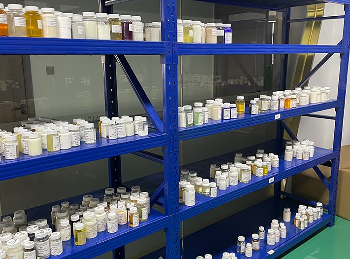 Blue metal laboratory shelving filled with numerous labeled white-capped bottles and jars on multiple shelves in a storage room.